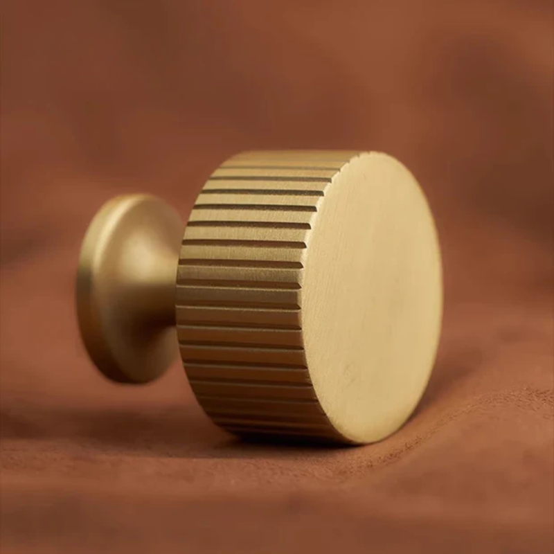 Gold cylindrical object with textured surface on a brown fabric background