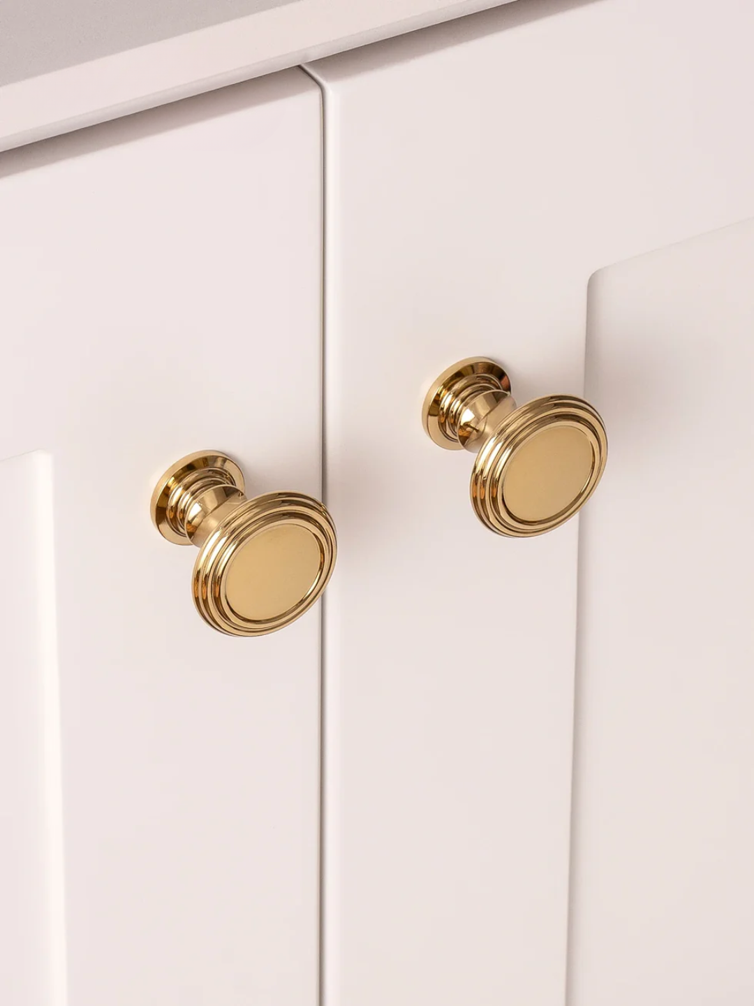 Close-up of gold cabinet knobs on a white cabinet