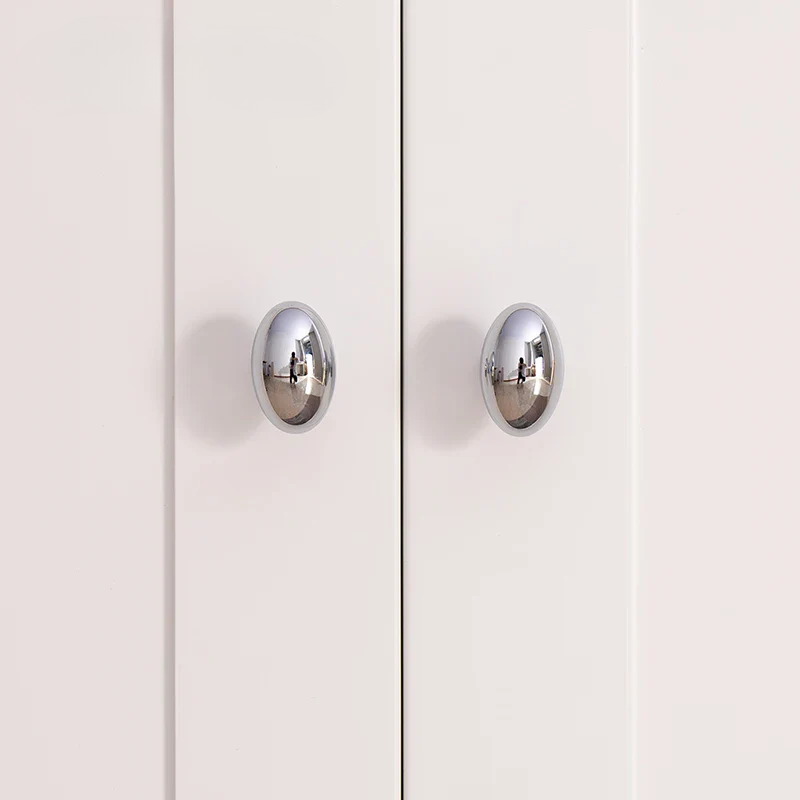 Close-up of a white cabinet with silver handles on a light pink background