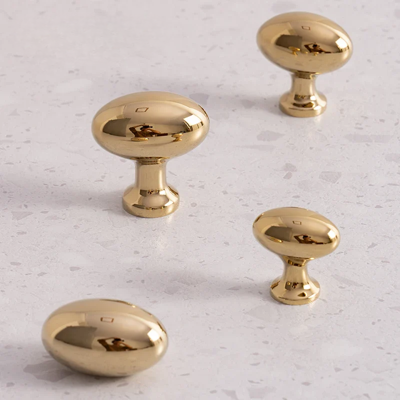 Four gold cabinet knobs on a light gray surface