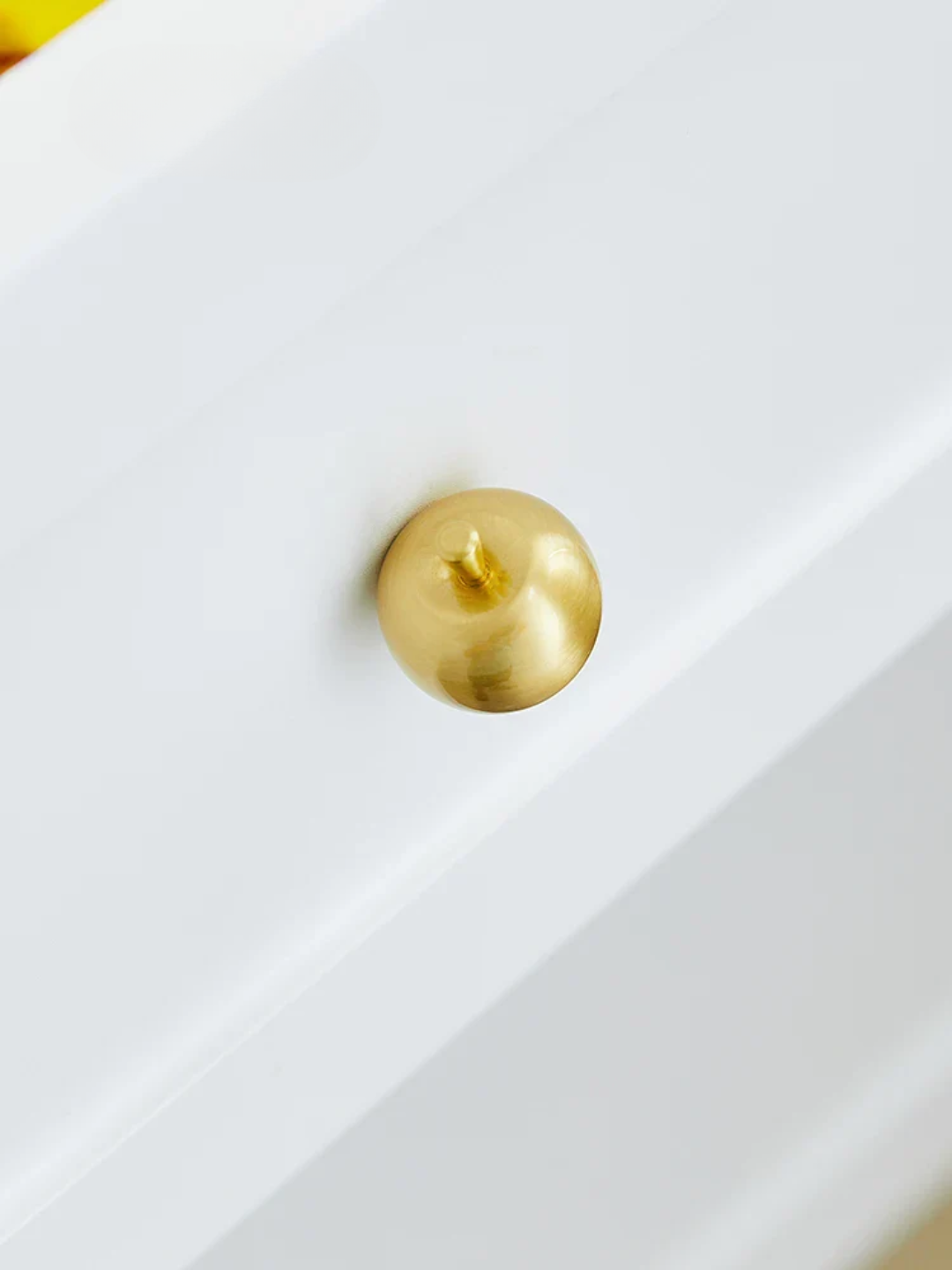 Gold knob on a white cabinet