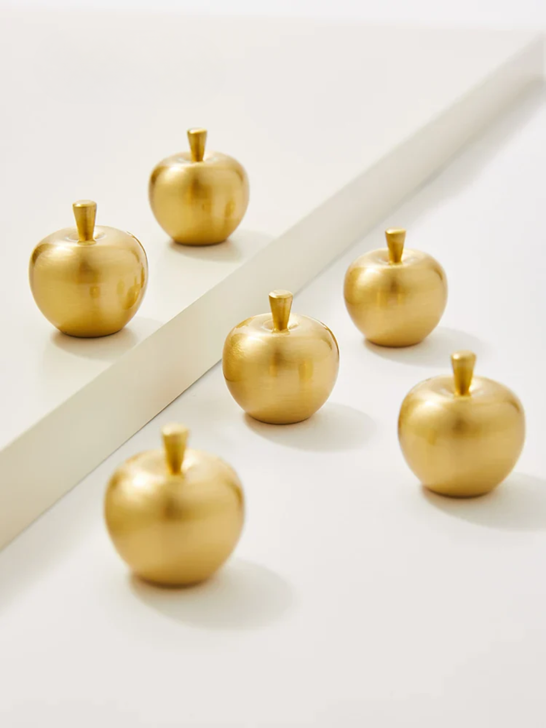 Gold apple-shaped objects on a white surface