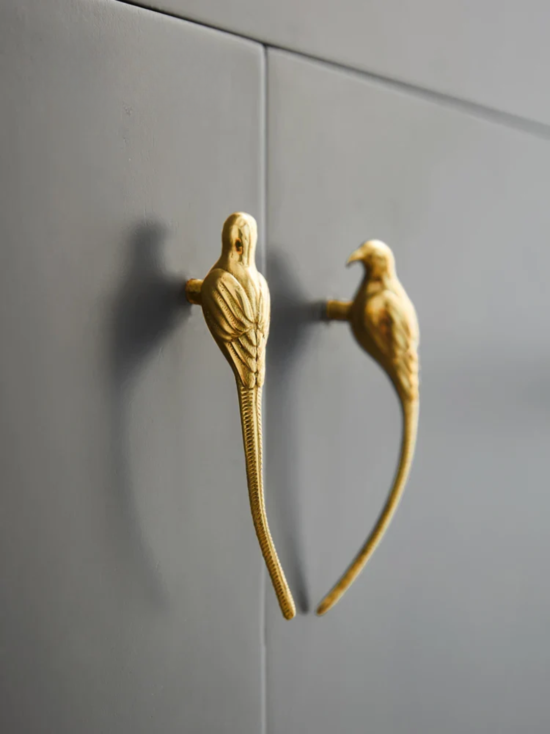 Gold bird-shaped cabinet handles on a gray cabinet