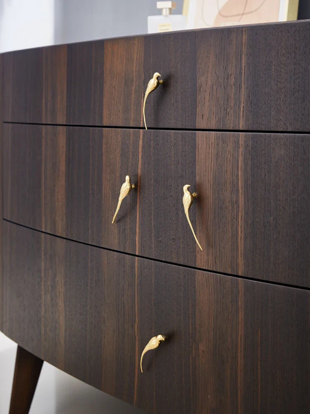 Wooden dresser with gold handles on a neutral background