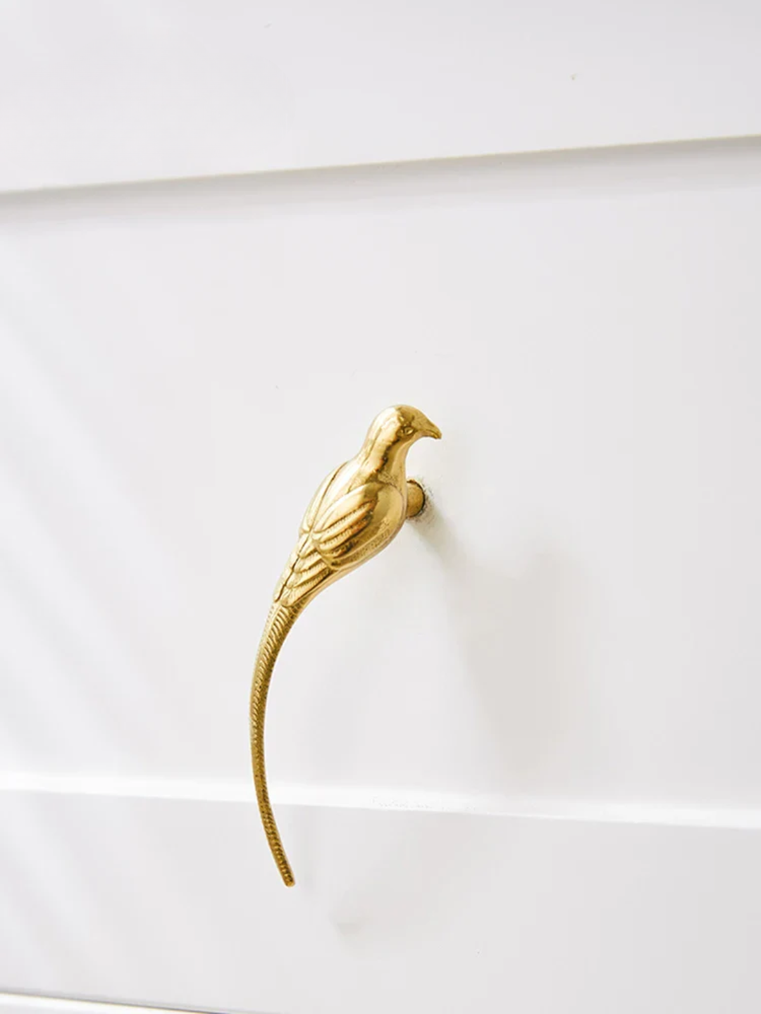 Gold bird-shaped handle on a white surface