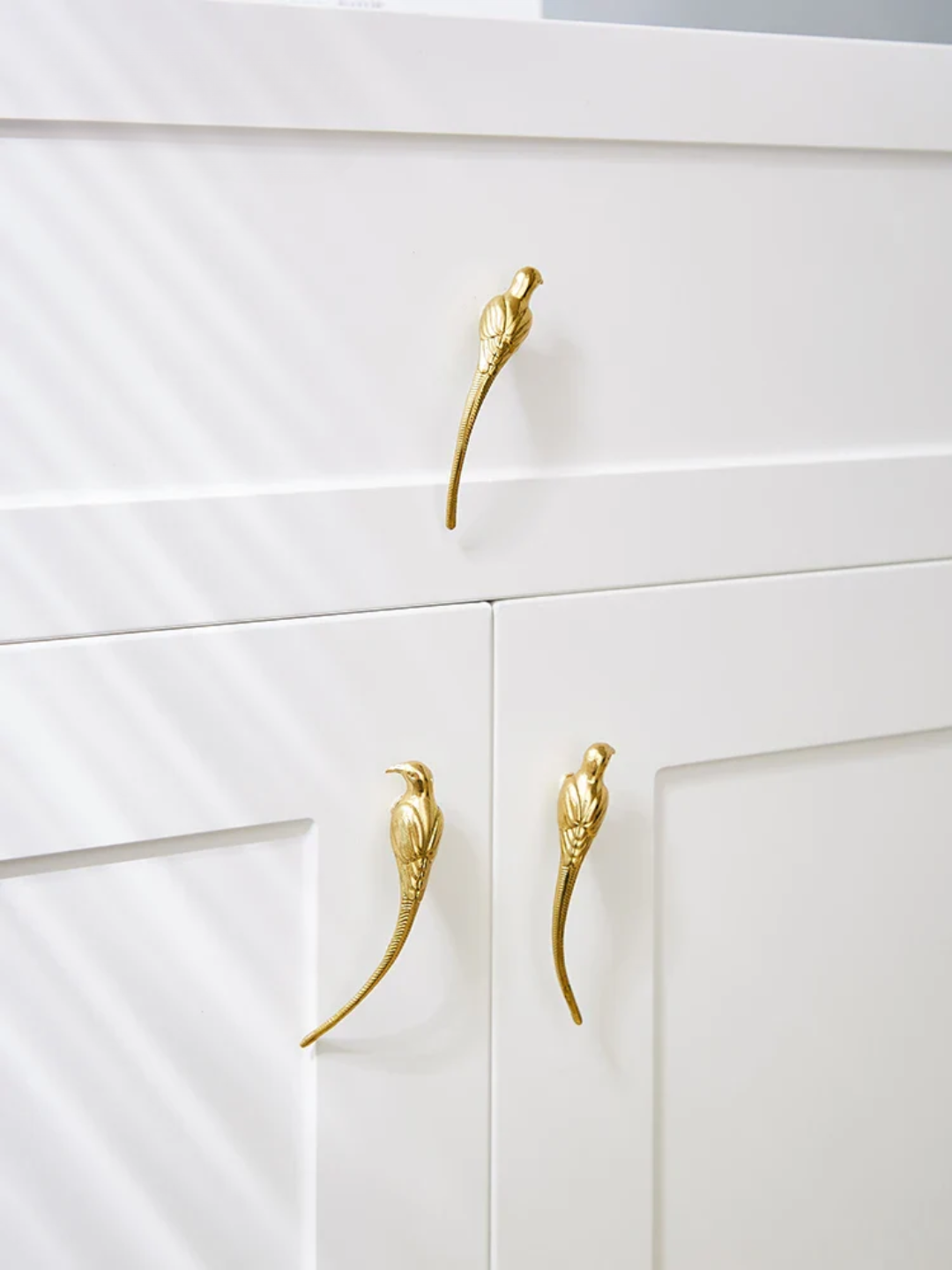 White cabinet with gold bird-shaped handles