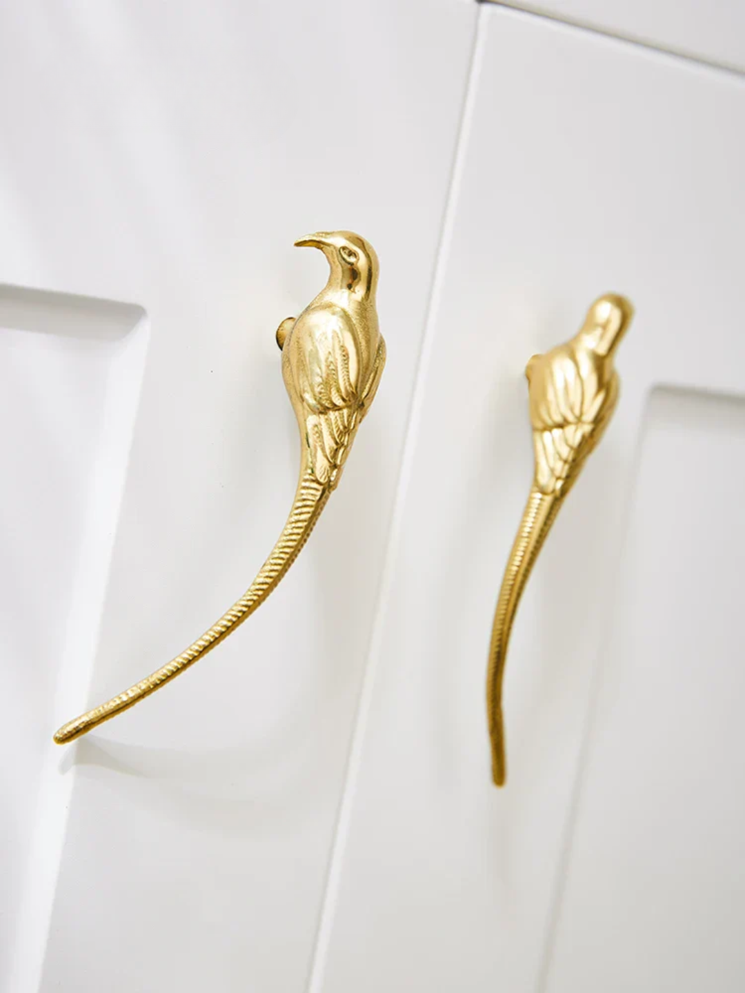 Gold bird-shaped earrings on a white surface