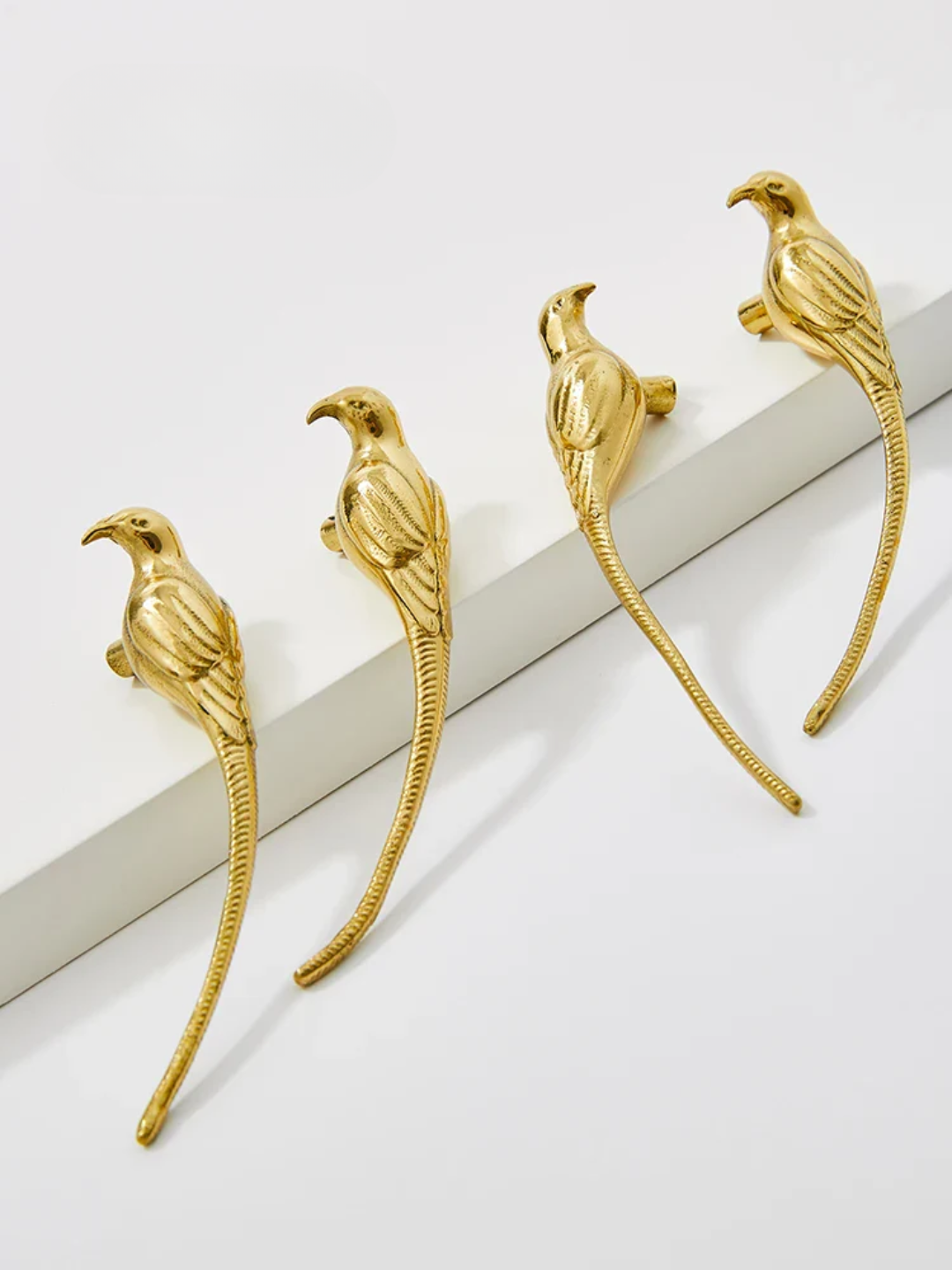 Gold bird-shaped earrings on a white surface