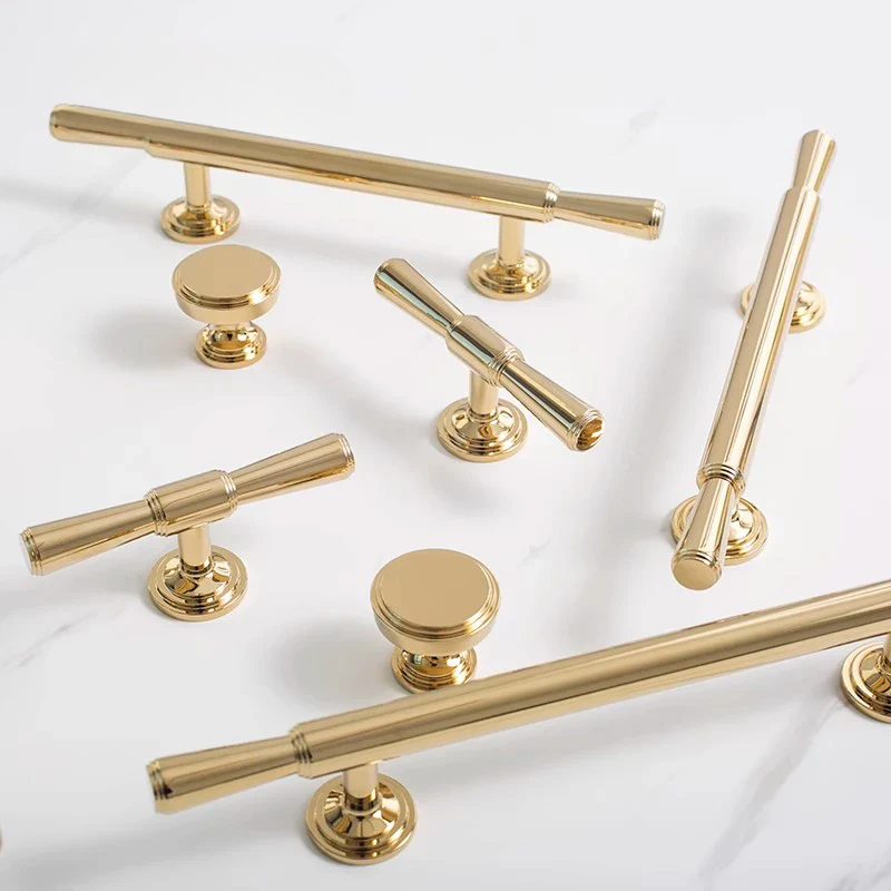 Gold cabinet handles and knobs on a white background