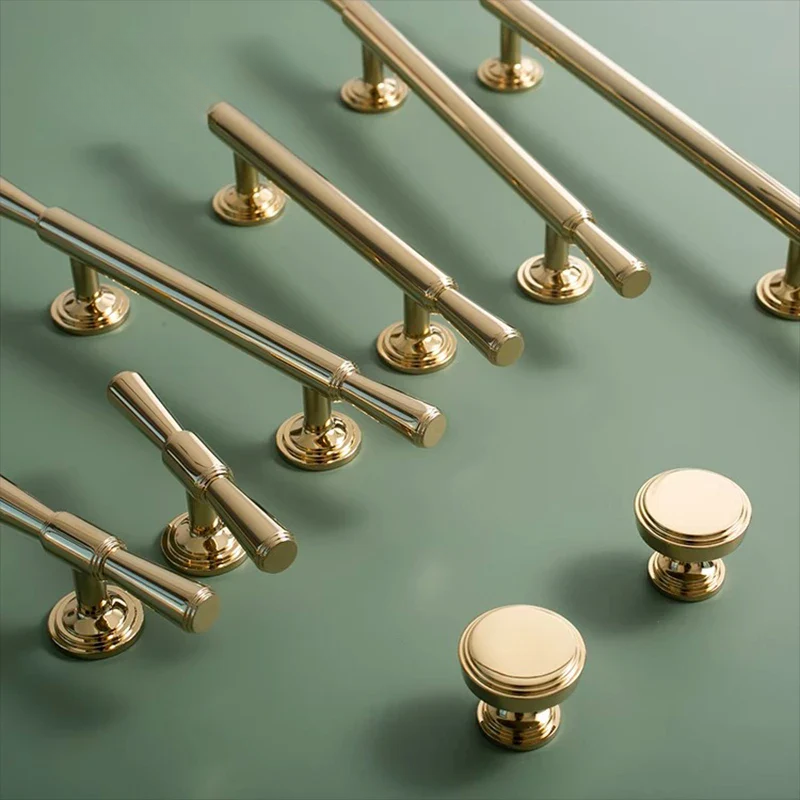 Set of gold cabinet handles and knobs on a green background