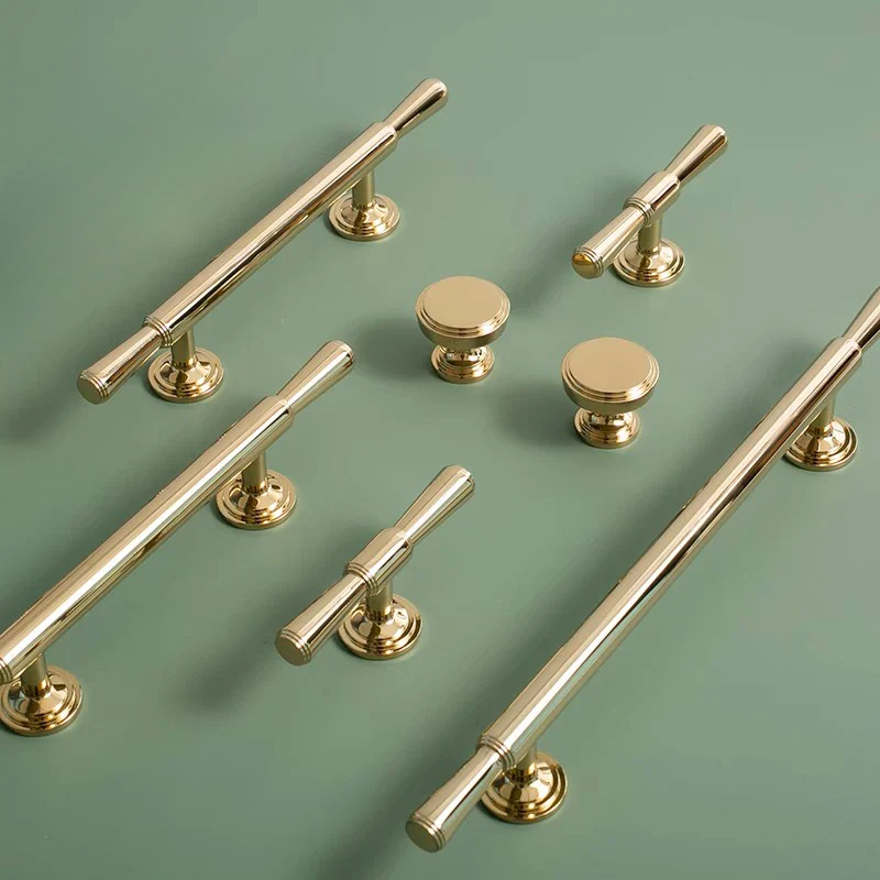 Set of gold cabinet handles and knobs on a green background