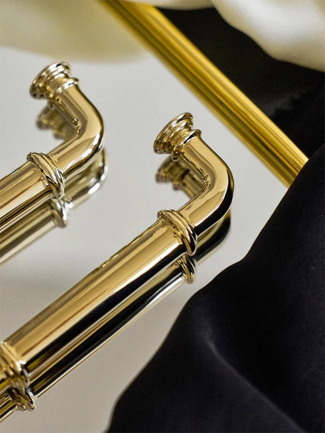 Gold bathroom handles on a mirror with a blurred background