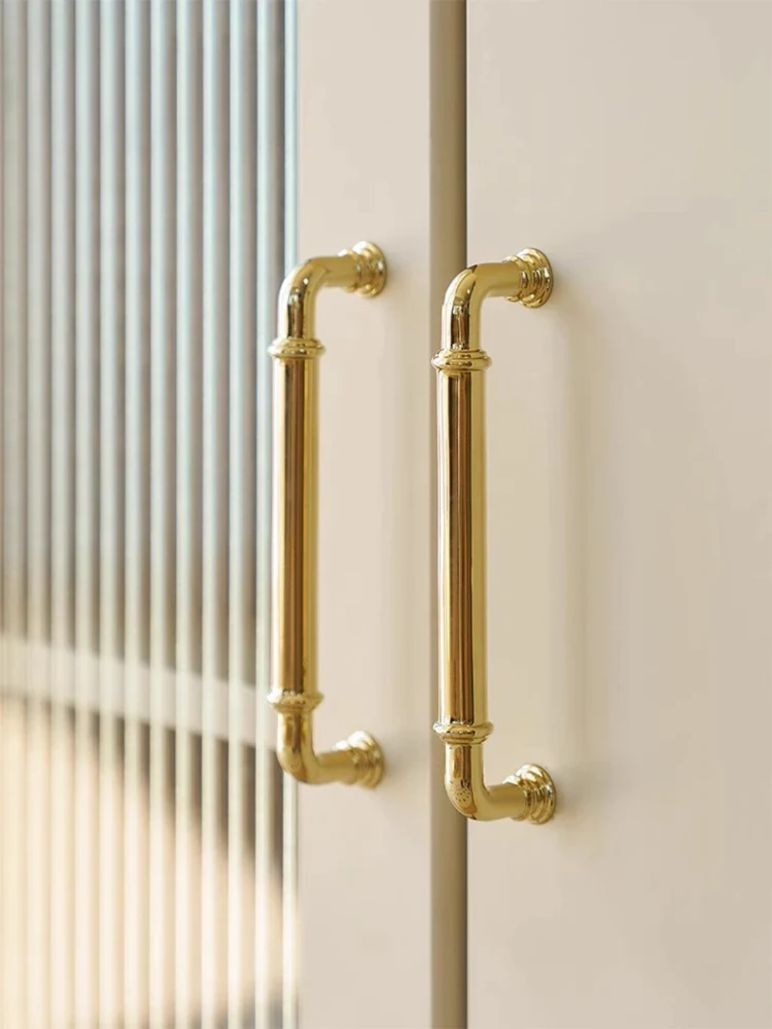 Gold cabinet handles on a white door with a blurred background