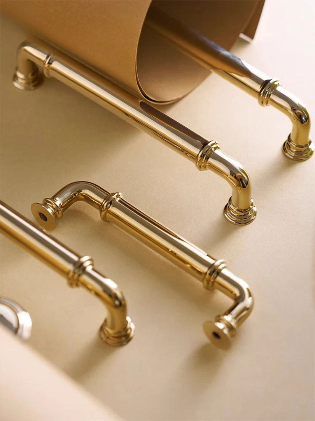 Gold pipe-style handles on a beige surface