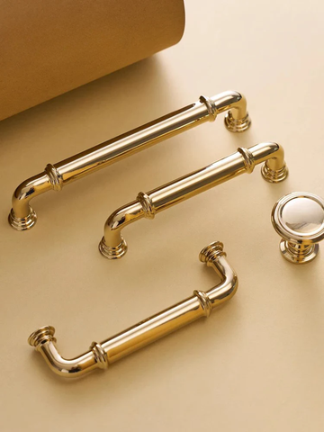Gold cabinet handles and knob on a beige background