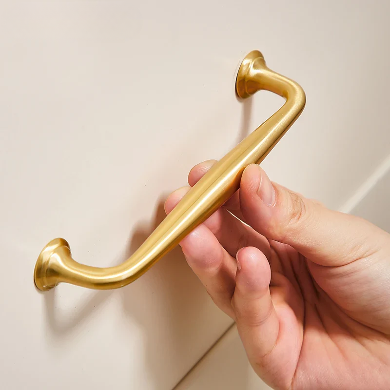 Hand holding a gold handle against a neutral background