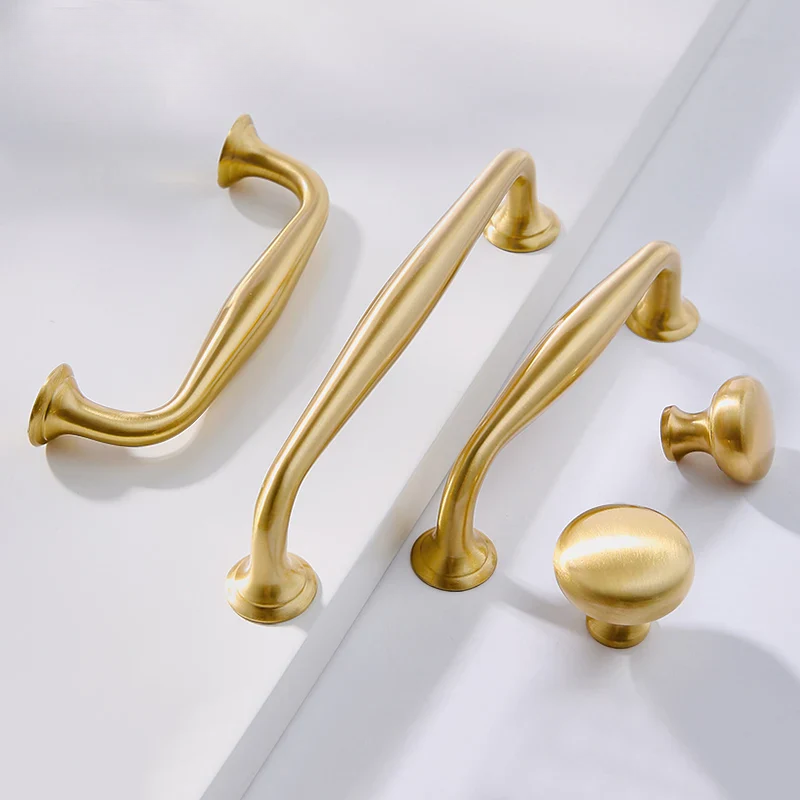 Set of gold cabinet handles and knobs on a white background