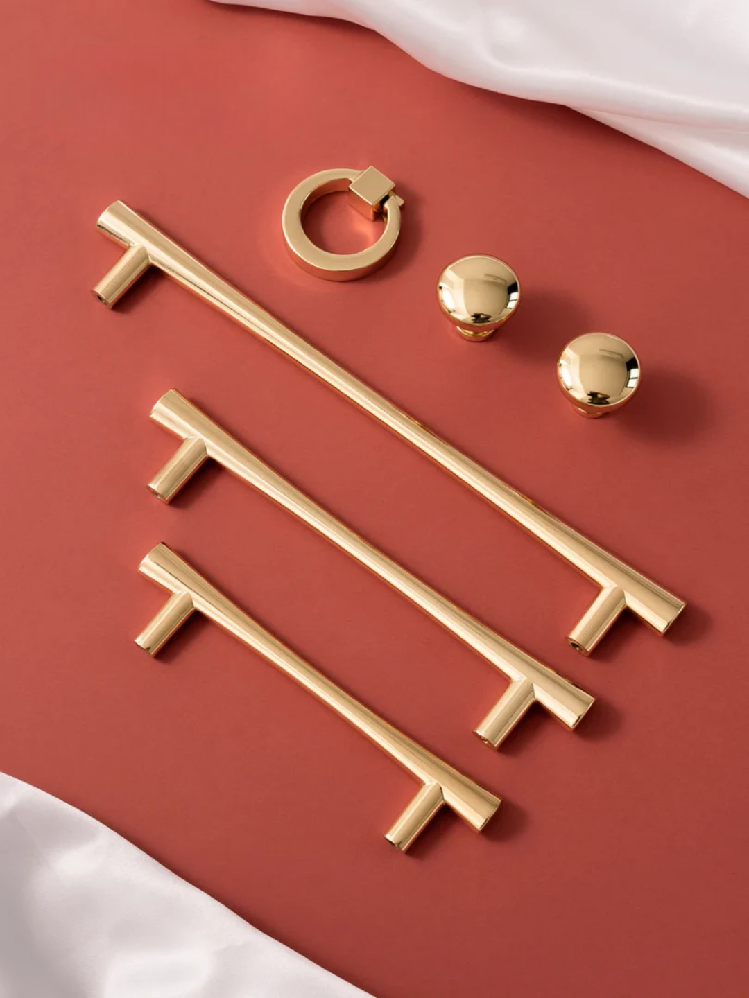 Set of gold cabinet handles and knobs on a red background