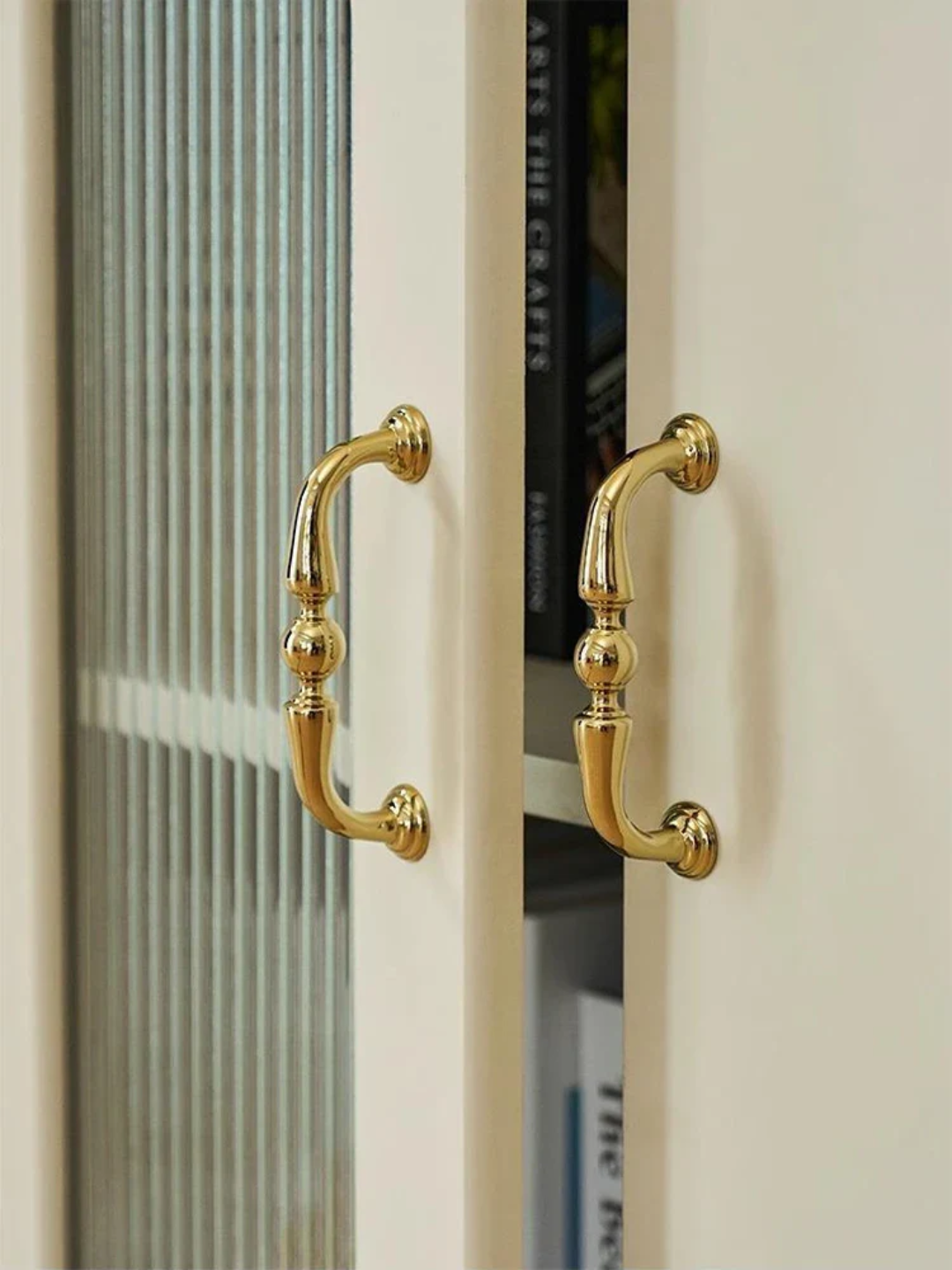 Close-up of a cabinet with gold handles on a neutral background