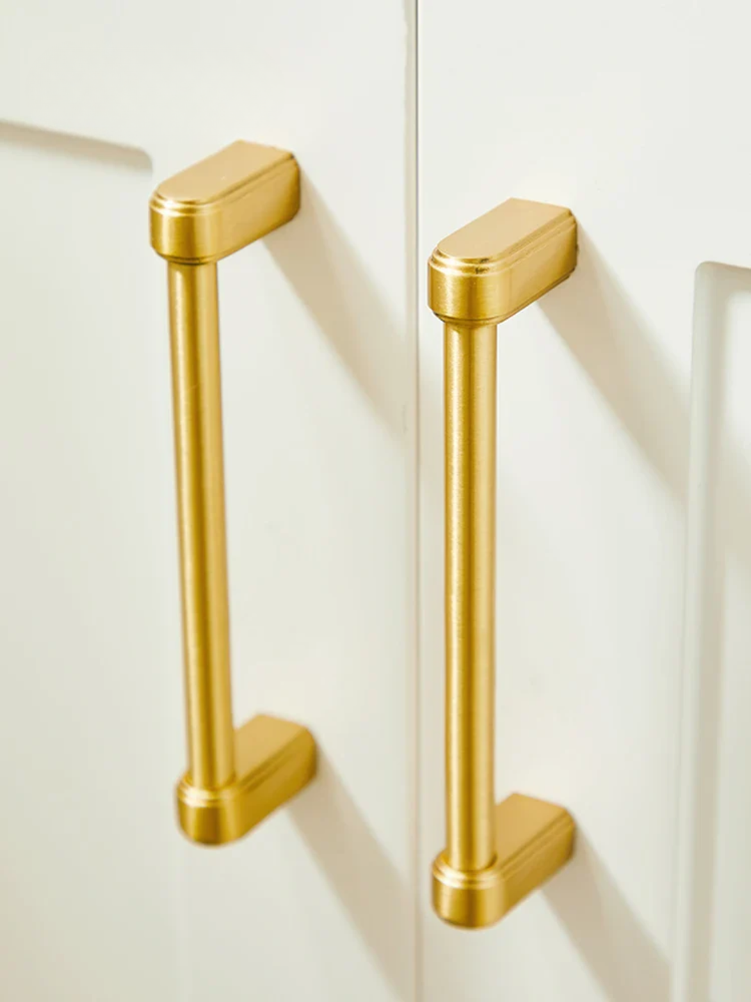 Two gold handles on a white cabinet