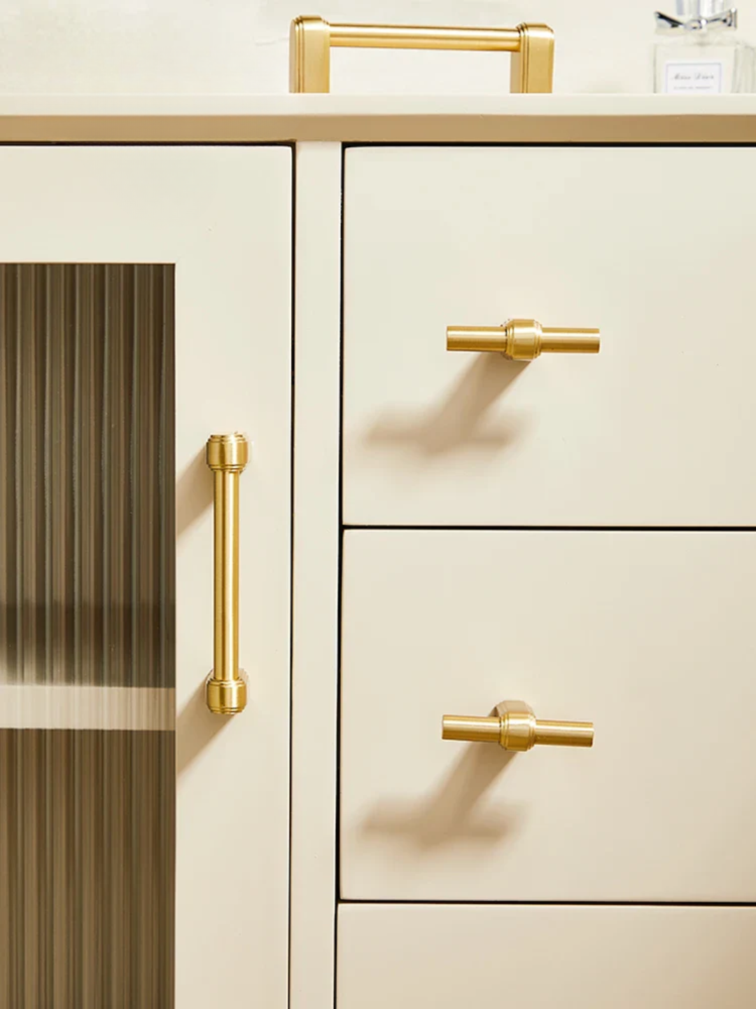 Beige kitchen cabinets with gold handles on a white background