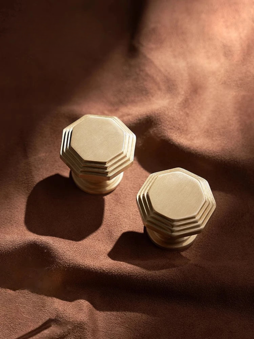 Two beige hexagonal knobs on a brown fabric background