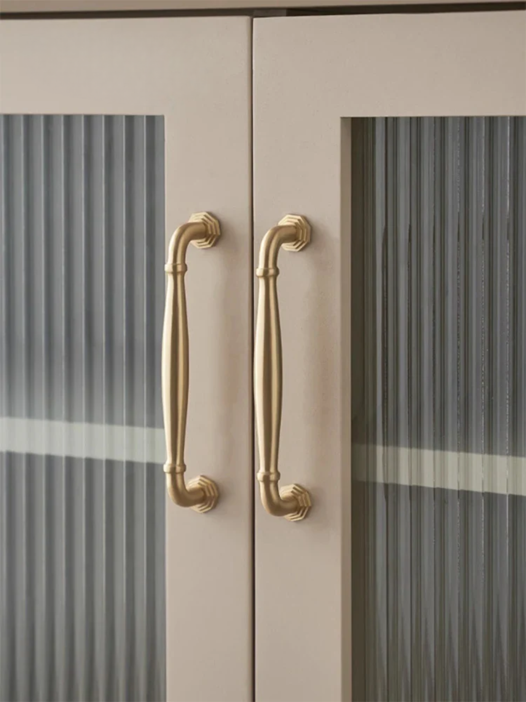 Close-up of a cabinet with gold handles and glass doors.