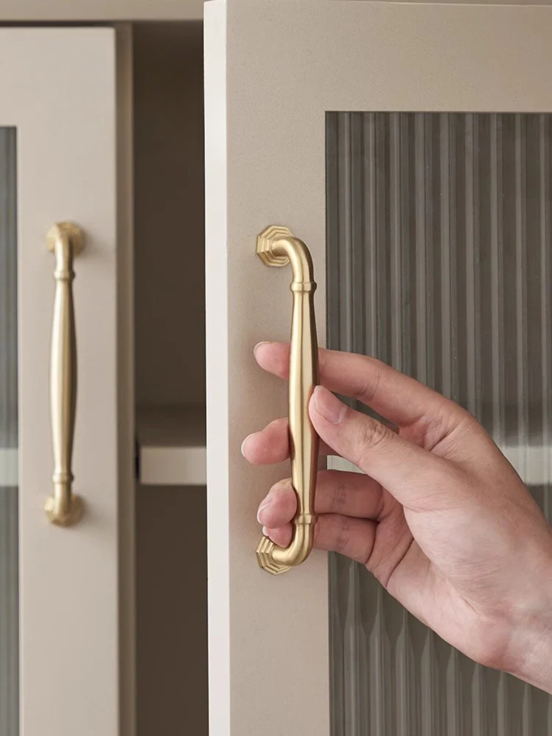 Hand opening a cabinet door with a gold handle