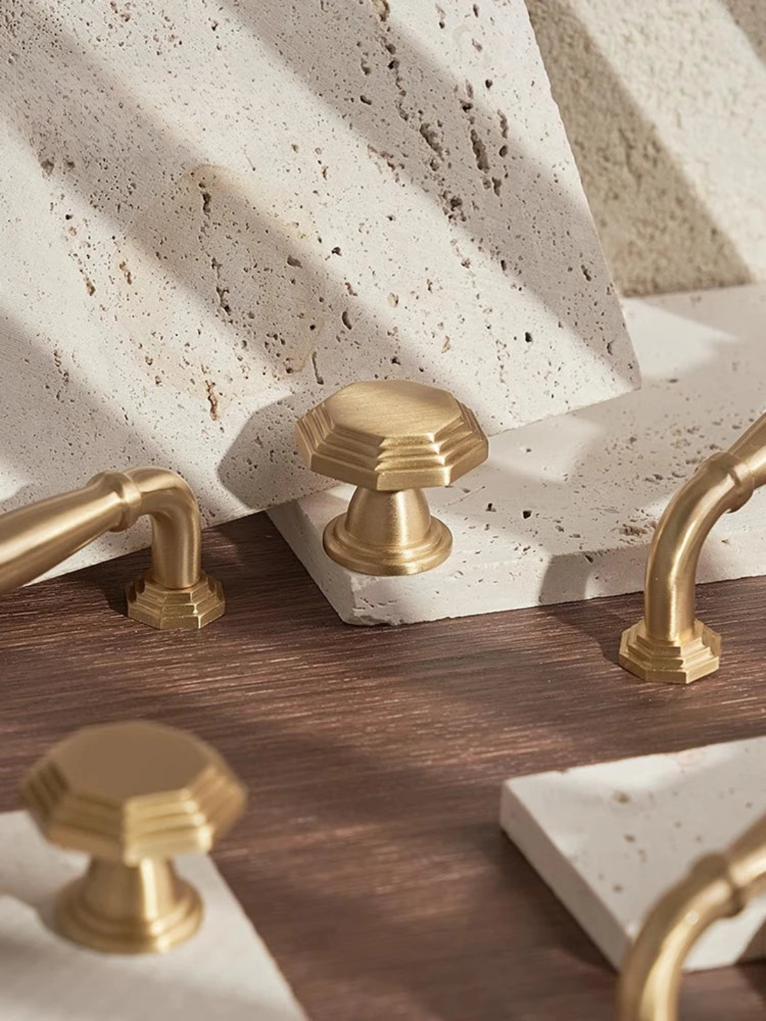 Gold faucet handles on a bathroom vanity with stone and wood finishes.