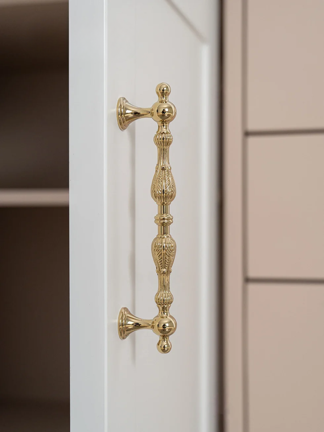 Gold cabinet handle on a white cabinet with a neutral background