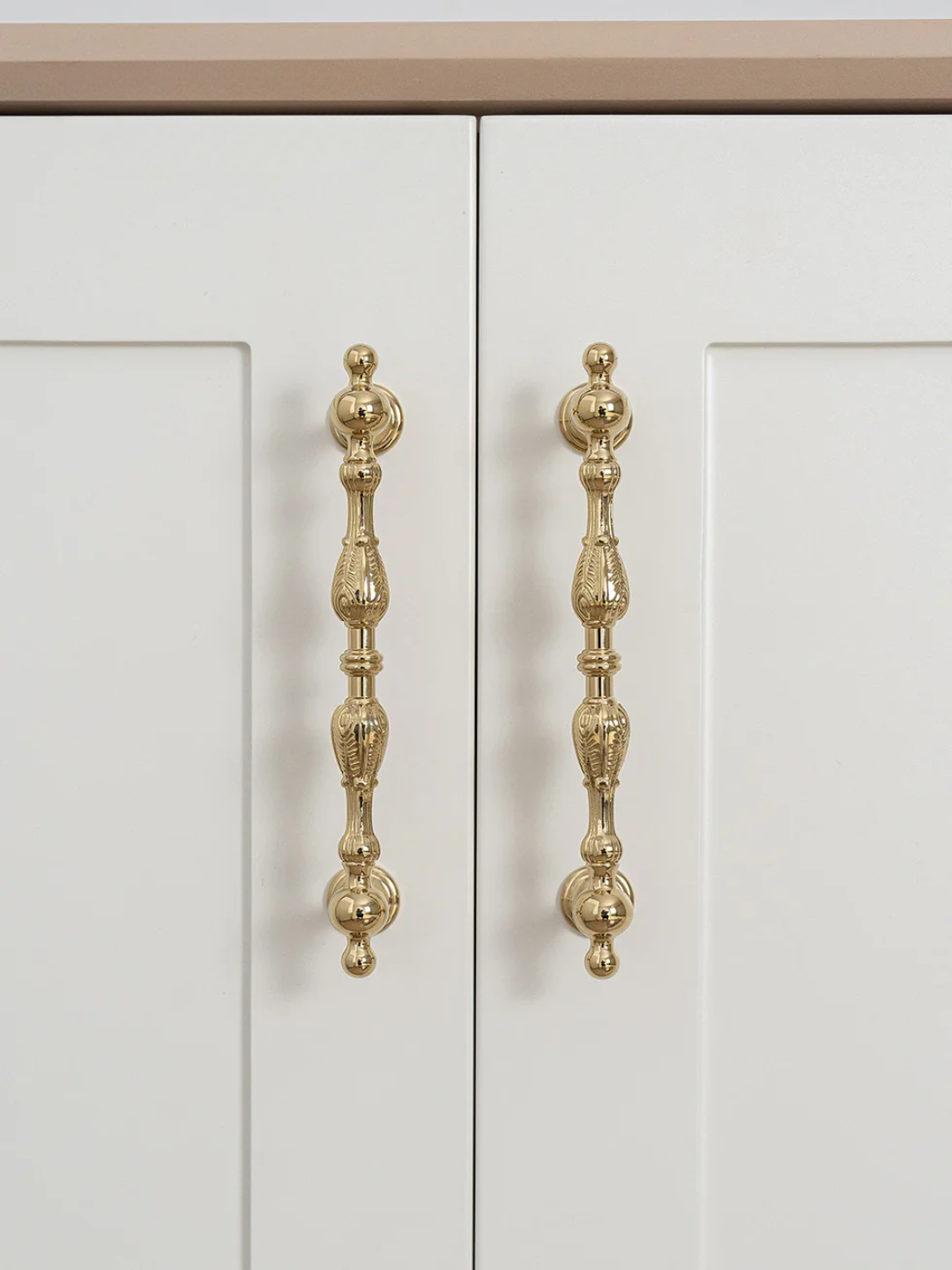 Close-up of a white cabinet with decorative gold handles