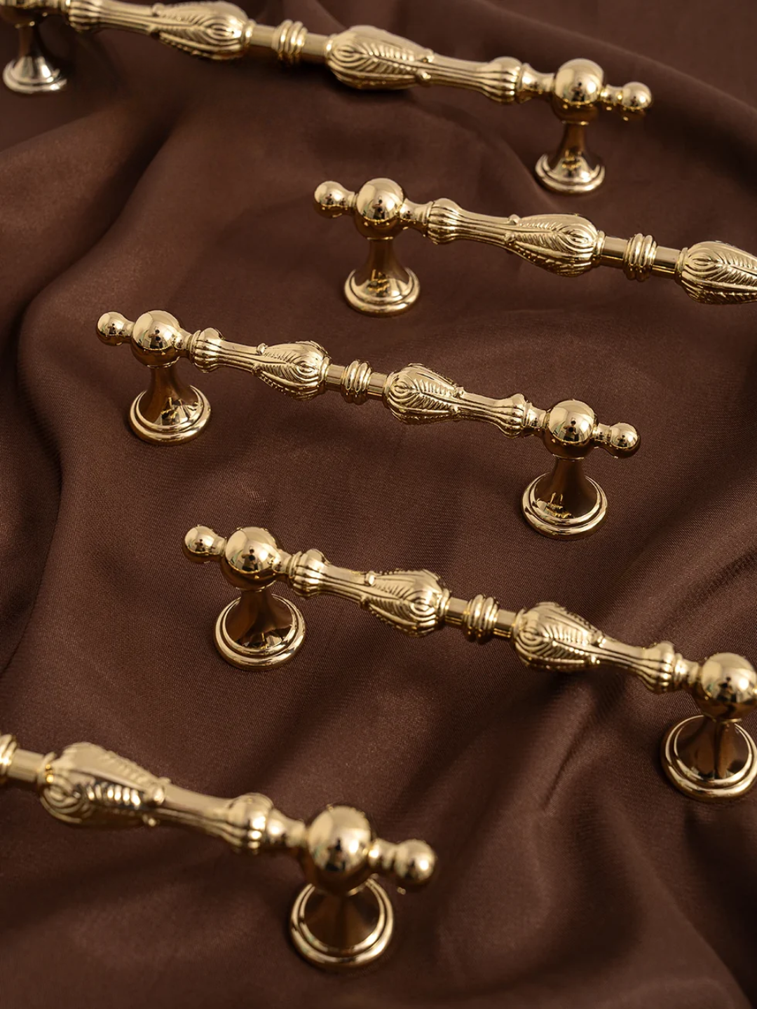 Gold cabinet handles on a brown fabric background