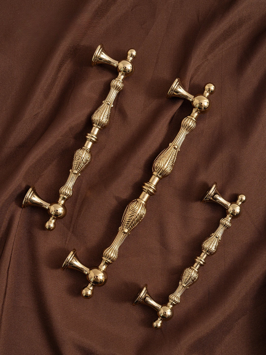 Set of gold decorative door handles on a brown fabric background