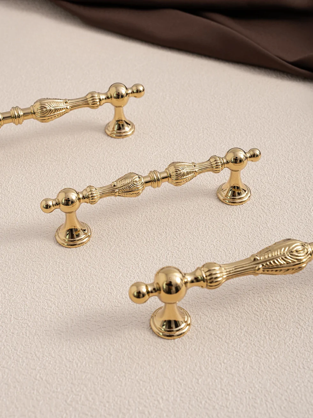 Set of gold cabinet handles on a beige surface
