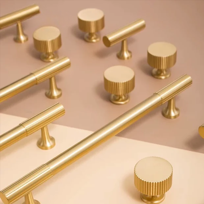 Gold cabinet handles and knobs on a beige background