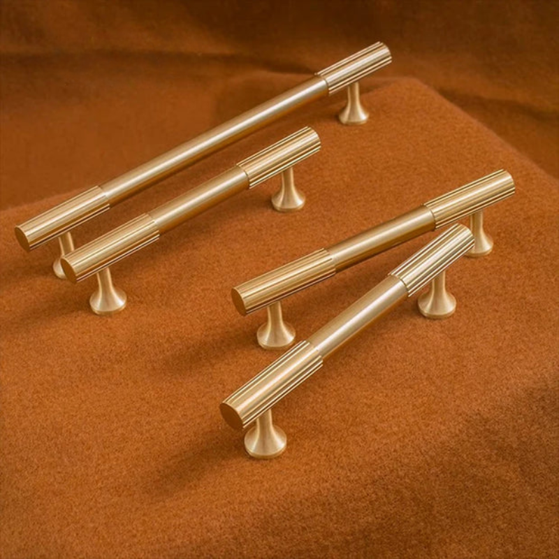 Set of gold cabinet handles on a brown fabric background