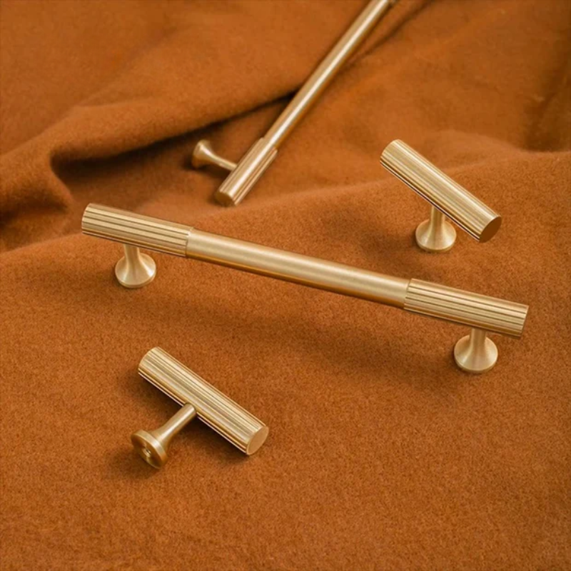 Gold cabinet handles on a brown fabric background