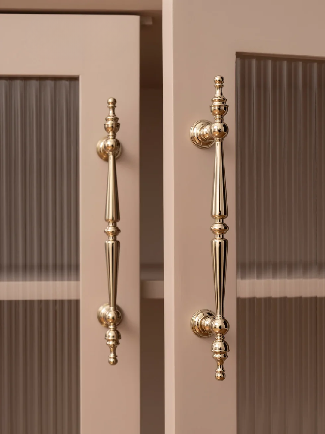 Gold cabinet handles on a beige cabinet with a neutral background