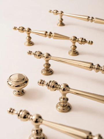 Collection of gold cabinet handles and knobs on a light background