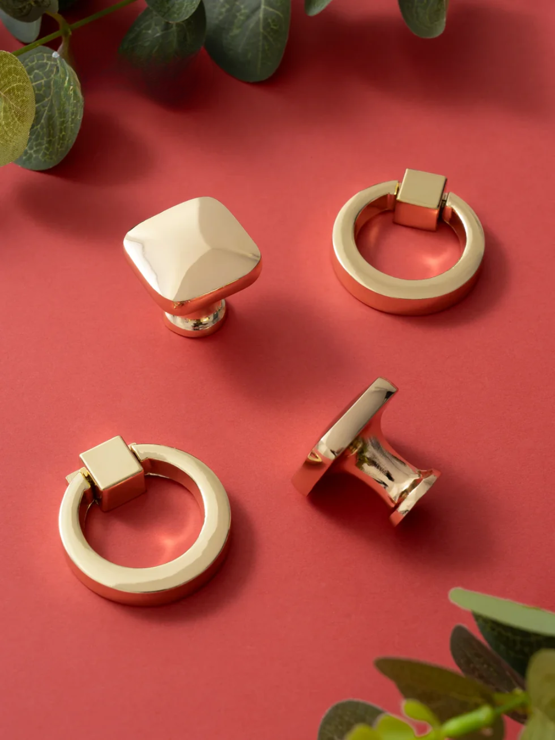 Decorative cabinet knobs on a red background with green leaves.