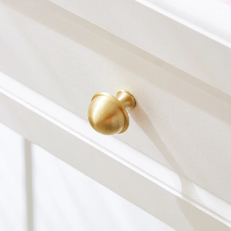 Gold cabinet knob on a white cabinet