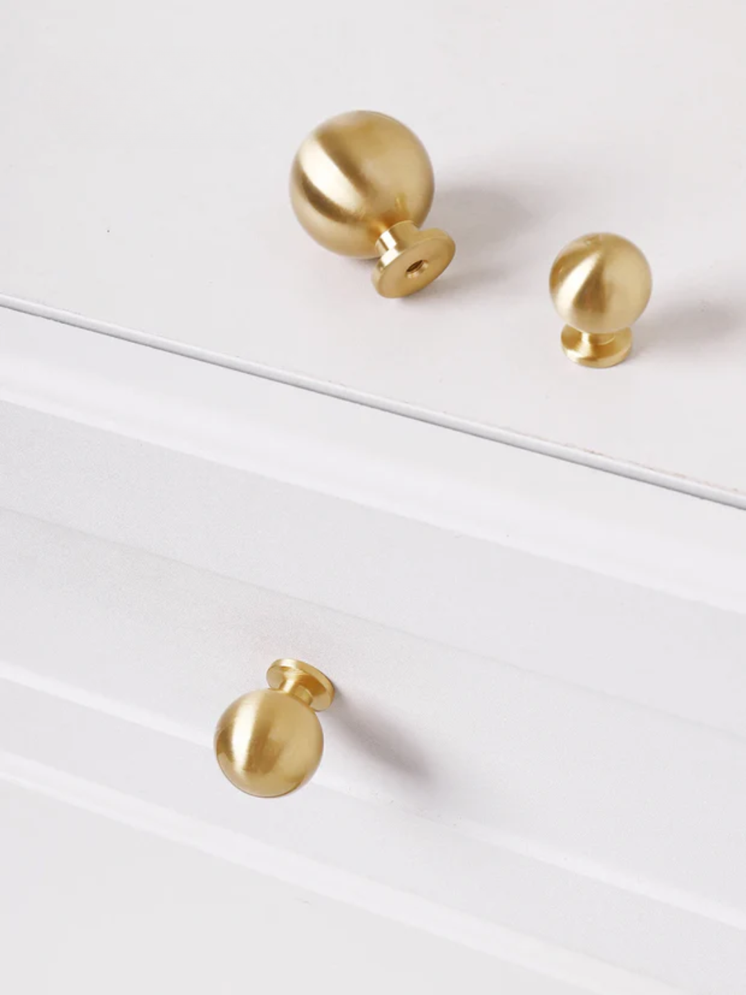 Three gold knobs on a white surface