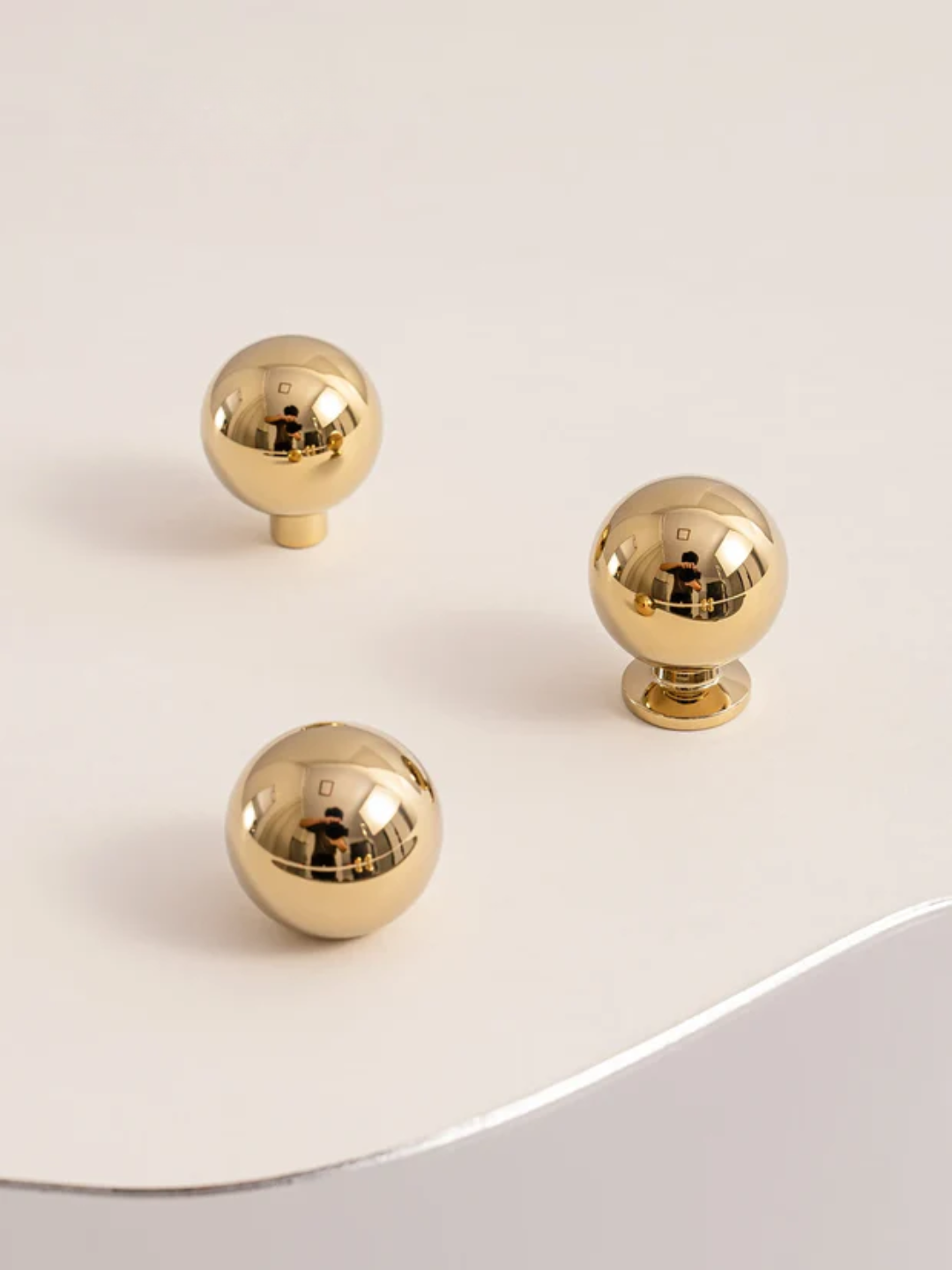 Three gold spherical knobs on a white surface