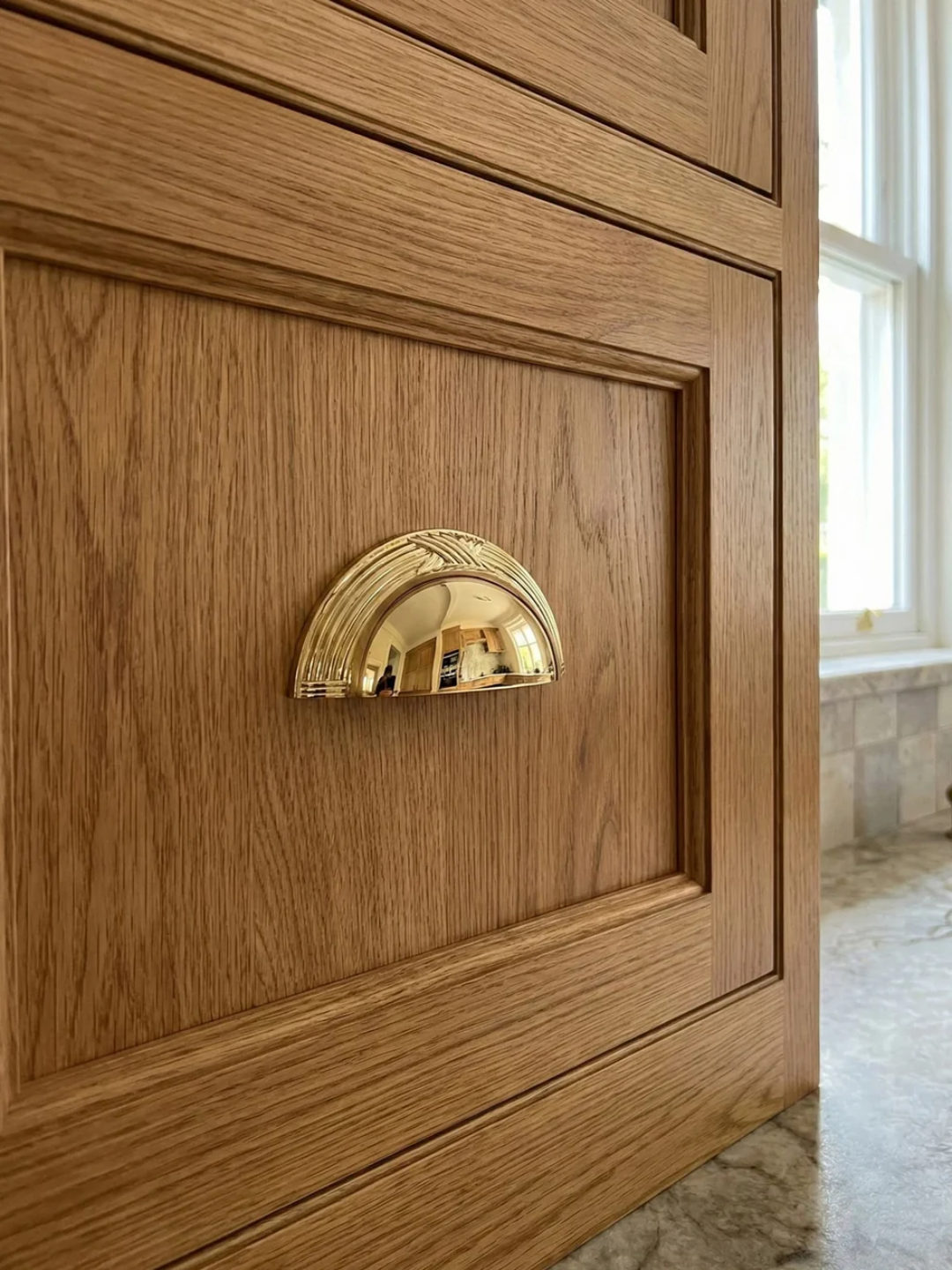 Wooden cabinet with a gold handle in a room with a window and marble floor.