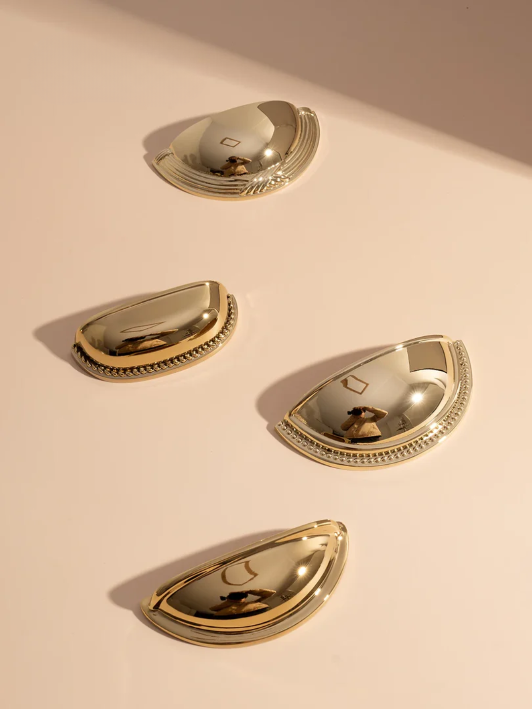 Four gold half-circle objects on a light beige background