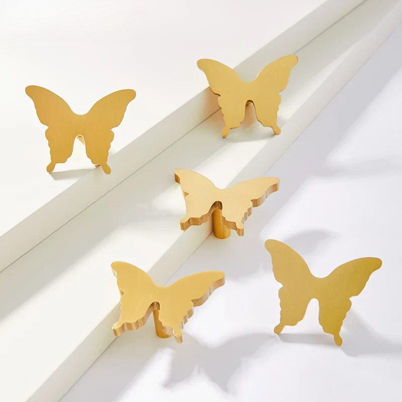 Five gold butterfly-shaped objects on a white surface