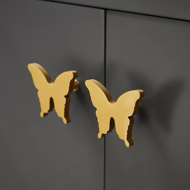 Gold butterfly-shaped cabinet handles on a black cabinet.