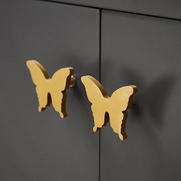 Gold butterfly-shaped cabinet handles on a black cabinet.