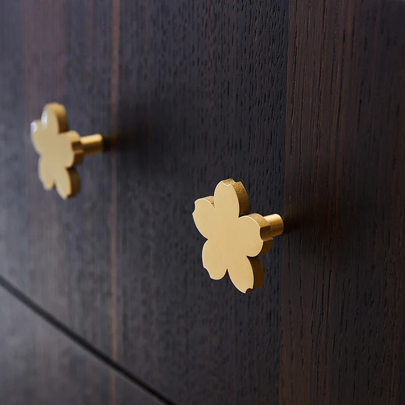 Gold flower-shaped cabinet knobs on a dark wooden surface