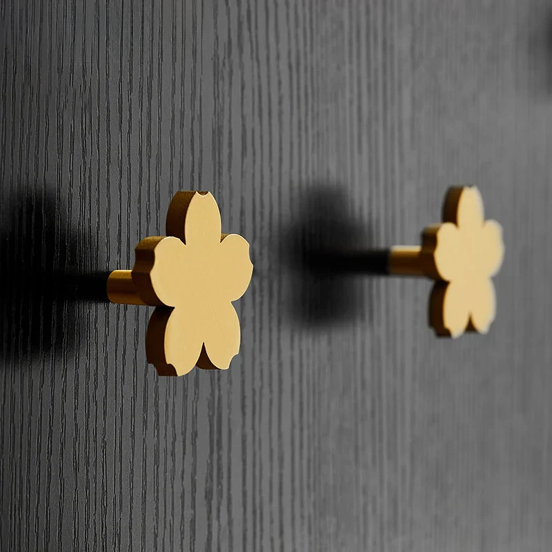 Gold flower-shaped earrings on a dark textured background